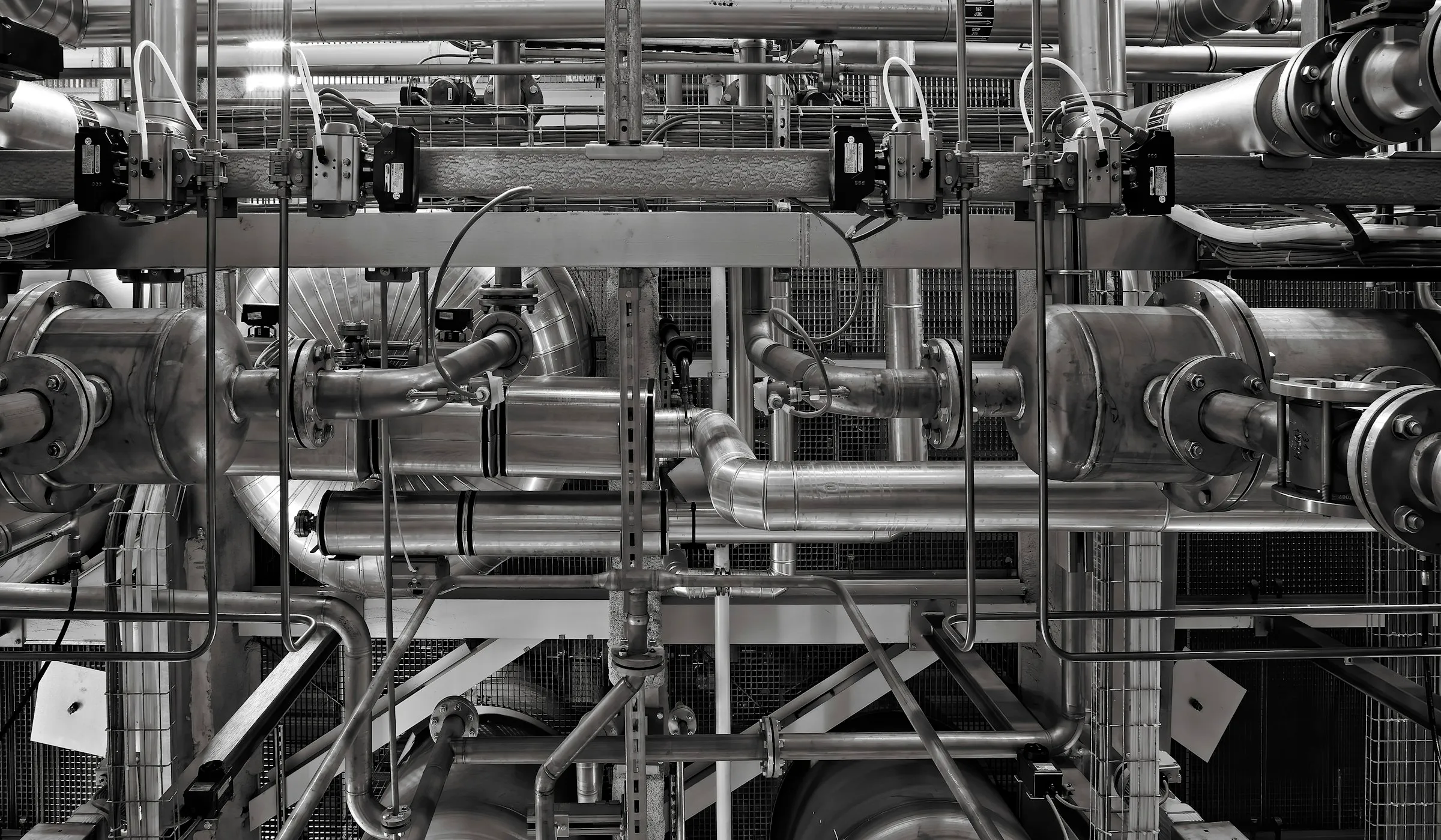 Industrial pipework and pressure vessels running across a plant gallery, with flanged joints and instrumentation